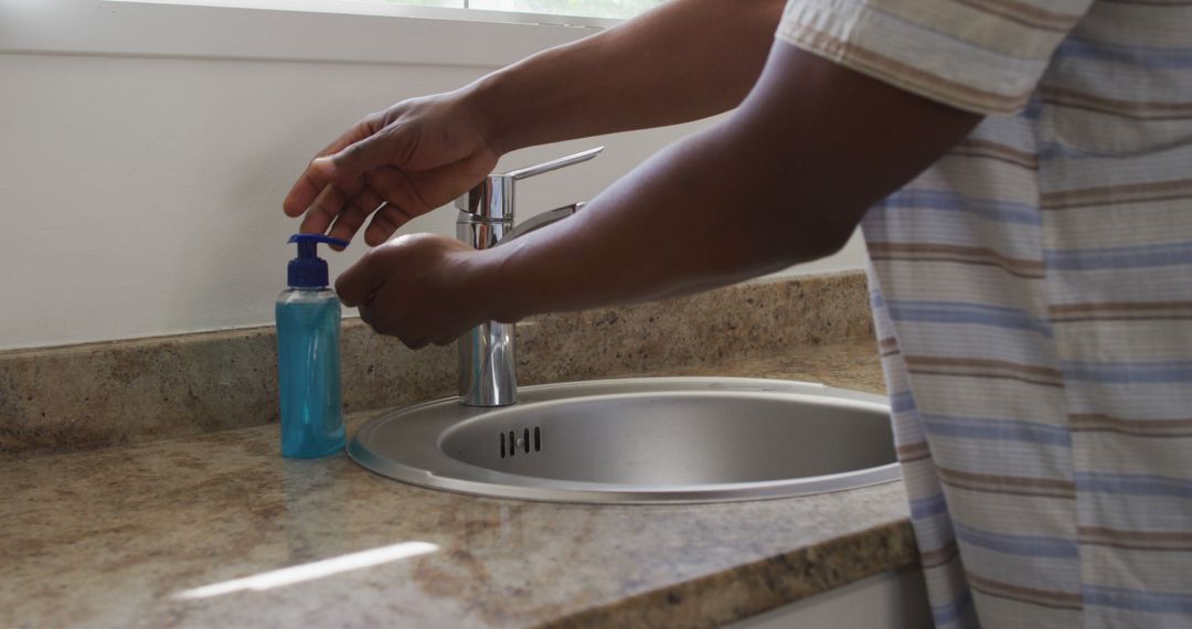 Person using liquid soap dispenser by kitchen sink - Free Images, Stock Photos and Pictures on Pikwizard.com