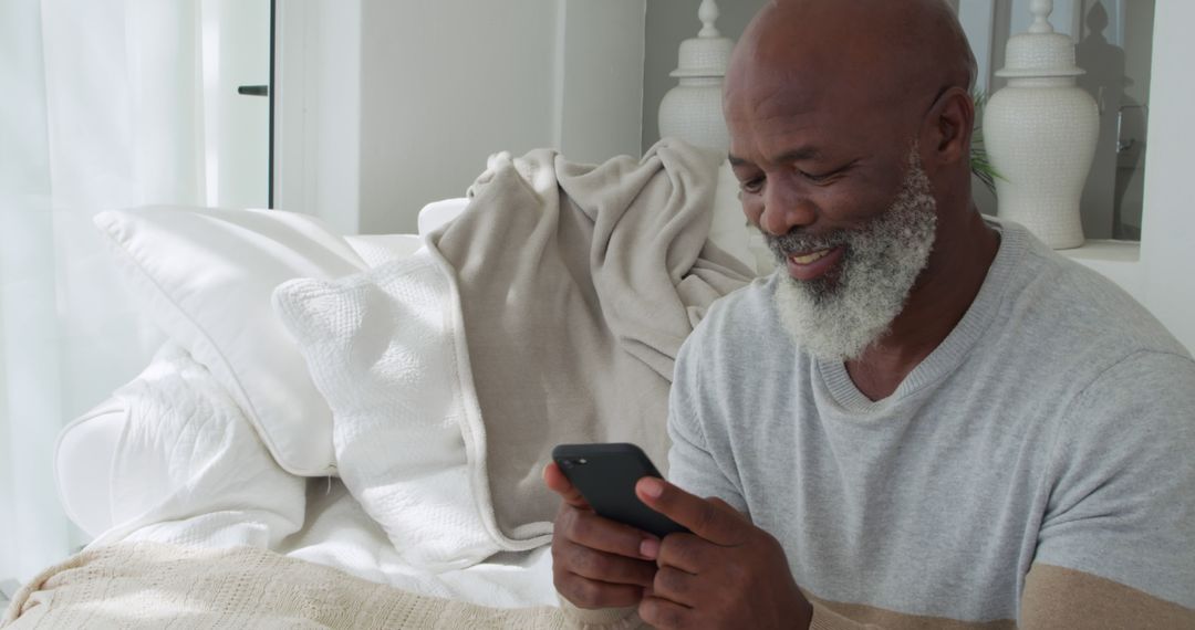 Smiling Elderly Man Enjoying Smartphone on Cozy Sofa at Home - Free Images, Stock Photos and Pictures on Pikwizard.com