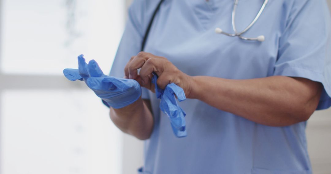 Healthcare Worker Putting on Disposable Gloves in a Medical Facility - Free Images, Stock Photos and Pictures on Pikwizard.com