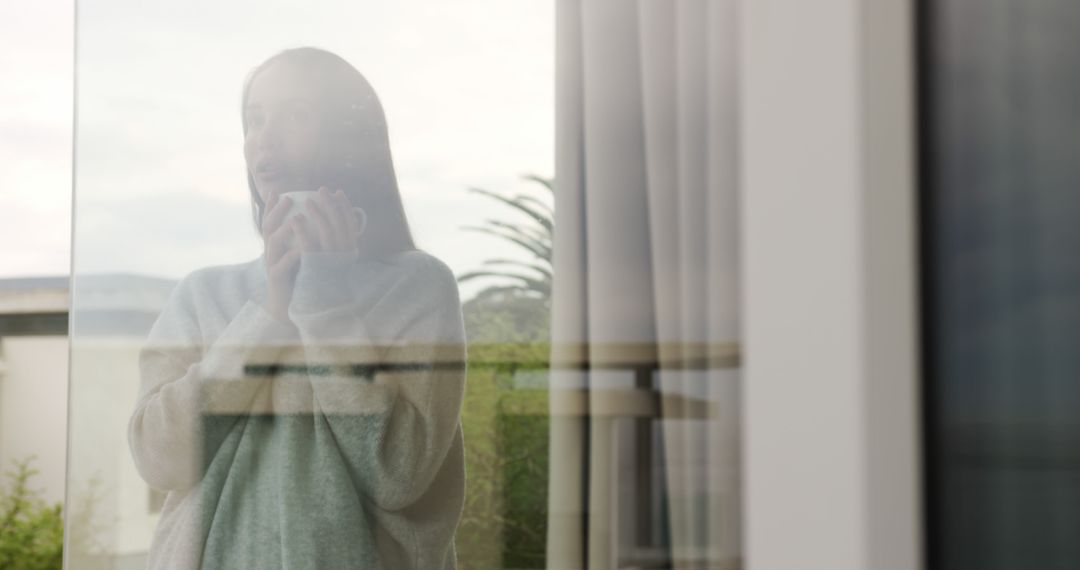 Woman Reflecting at Window with Hot Drink During Overcast Day - Free Images, Stock Photos and Pictures on Pikwizard.com