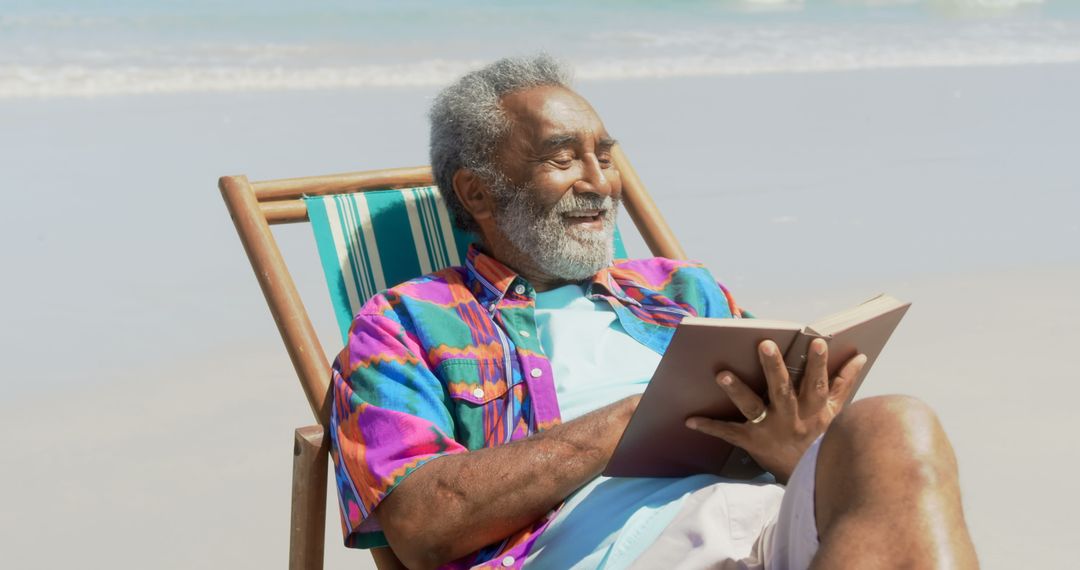 Senior Man Relaxing at Beach Reading Book and Enjoying Sunny Day