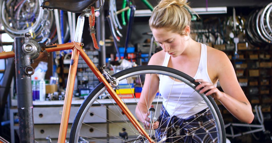 Woman Repairing Bicycle Tire in Workshop - Free Images, Stock Photos and Pictures on Pikwizard.com