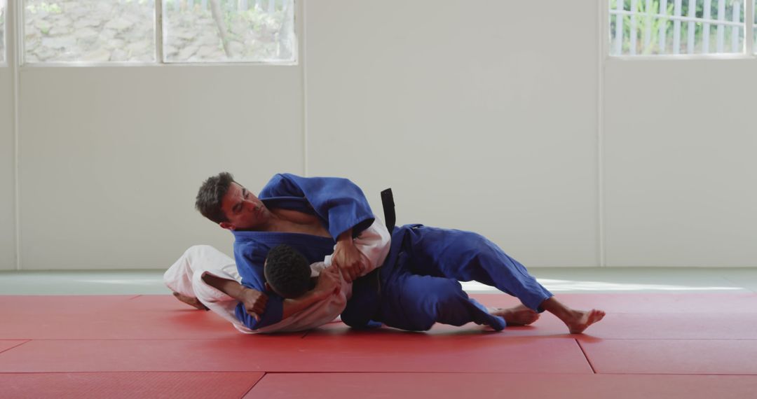 Two Men Practicing Judo Grappling Techniques on Mat - Free Images, Stock Photos and Pictures on Pikwizard.com