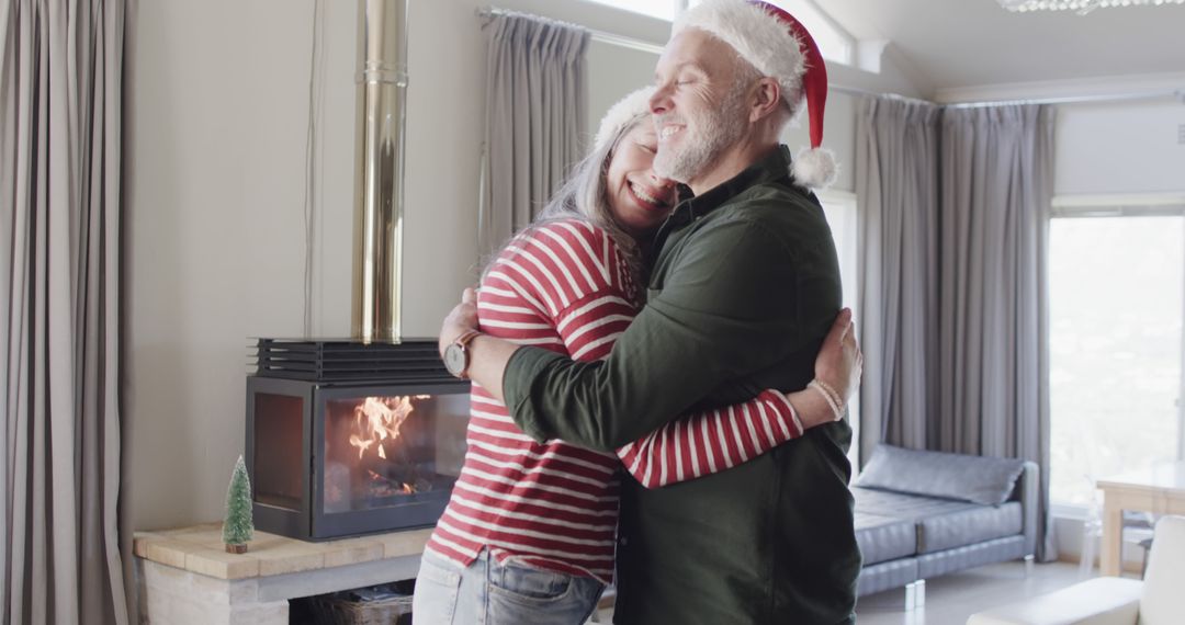Happy Senior Couple Hugging in Christmas Hats by Fireplace - Free Images, Stock Photos and Pictures on Pikwizard.com