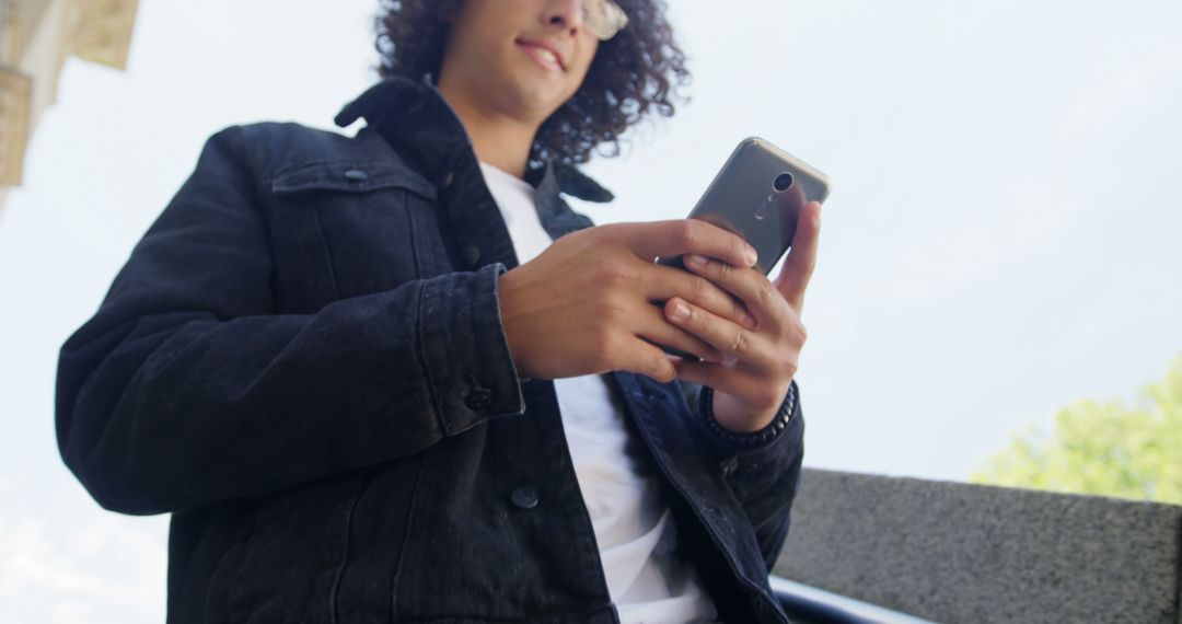 Young Man Texting on Smartphone Outdoors in Casual Denim Jacket - Free Images, Stock Photos and Pictures on Pikwizard.com