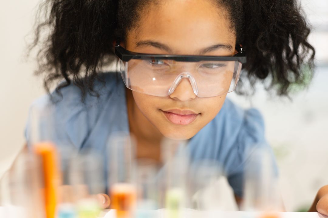 Close-up of biracial elementary schoolgirl wearing protective eyewear looking at chemicals - Free Images, Stock Photos and Pictures on Pikwizard.com