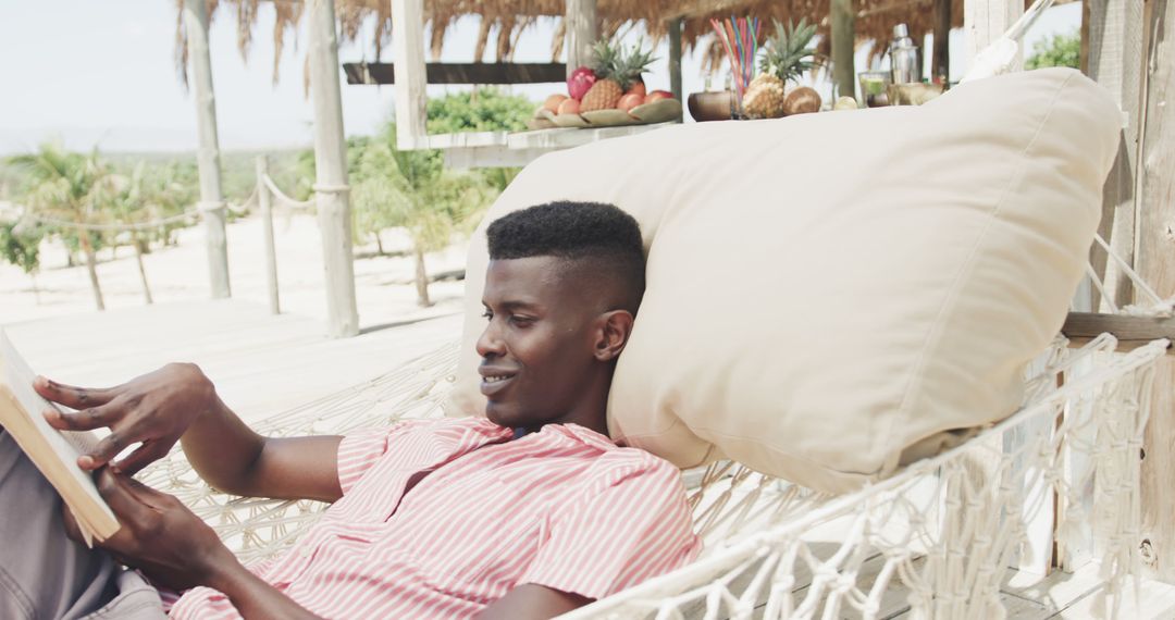 Young Man Relaxing on Hammock Reading Book at Tropical Beach Resort - Free Images, Stock Photos and Pictures on Pikwizard.com