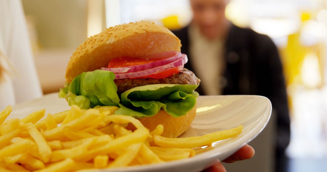 Close-Up of Delicious Burger with Fresh Lettuce, Onions, and French Fries on Ceramic Plate - Free Images, Stock Photos and Pictures on Pikwizard.com