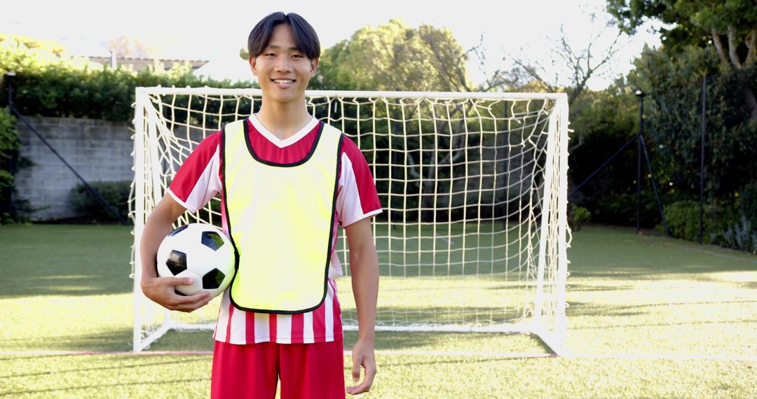 Teenage Soccer Player Smiling on Field with Ball