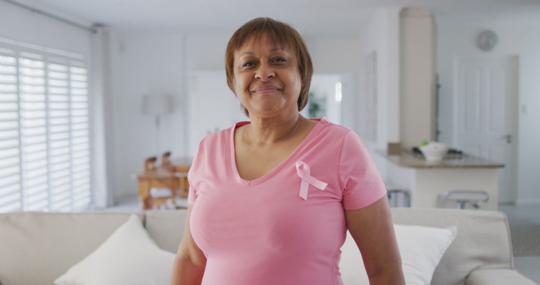 Smiling Woman Wearing Pink Ribbon for Breast Cancer Awareness at Home - Free Images, Stock Photos and Pictures on Pikwizard.com