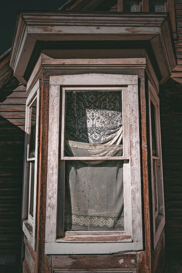 Weathered Victorian Bay Window with Lace Curtains, Peeling Paint and Rustic Wood Details