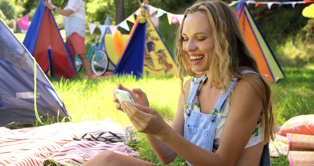 Happy Woman Enjoying Camping Trip Checking Smartphone in Park - Free Images, Stock Photos and Pictures on Pikwizard.com