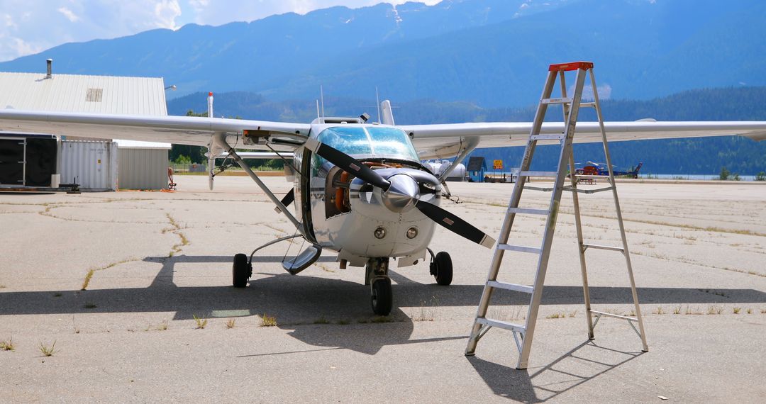 Small Airplane on Airfield with Ladder and Mountain Background - Free Images, Stock Photos and Pictures on Pikwizard.com