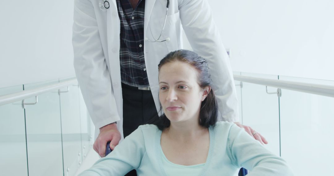 Doctor Assisting Female Patient in Wheelchair in Hospital Corridor - Free Images, Stock Photos and Pictures on Pikwizard.com