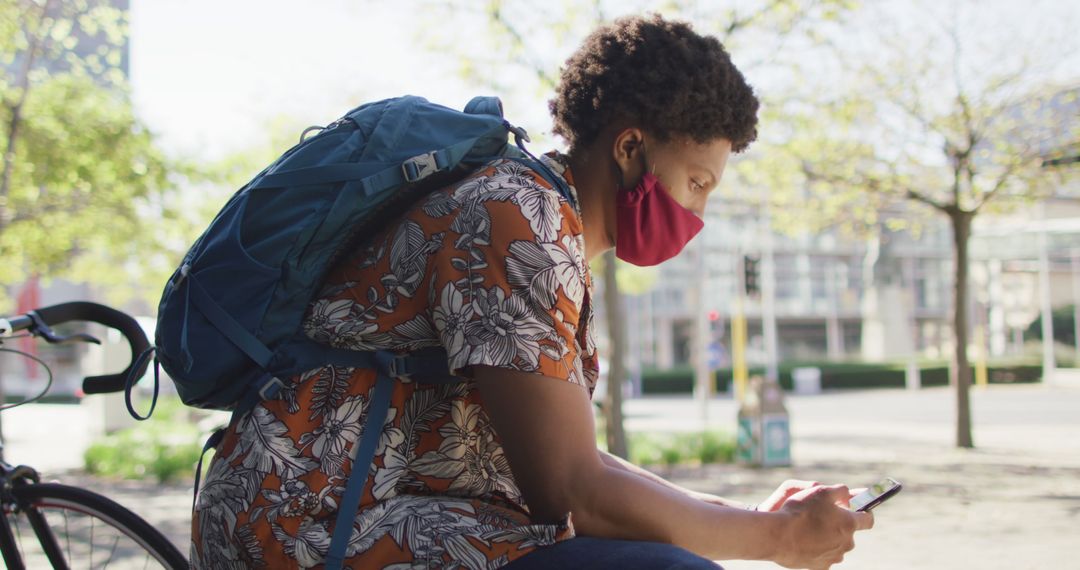 Young Man with Backpack Using Smartphone Outdoors