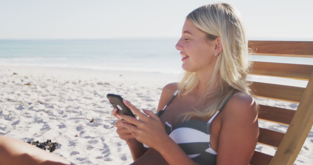 Blonde woman relaxing on sunny beach using smartphone - Free Images, Stock Photos and Pictures on Pikwizard.com