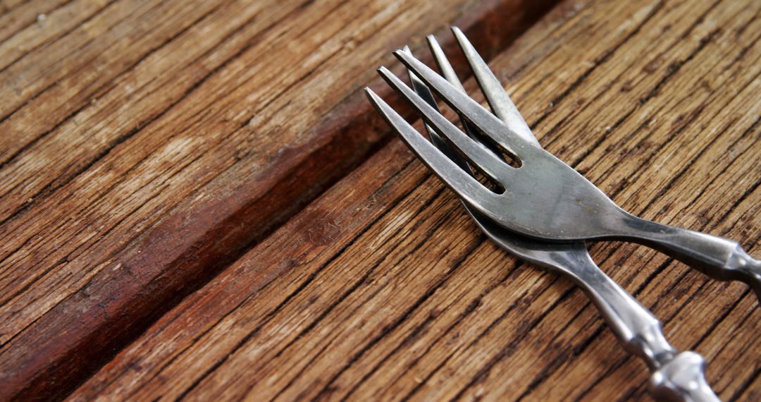 A pair of silver forks rests on a textured wooden surface, with copy space - Free Images, Stock Photos and Pictures on Pikwizard.com
