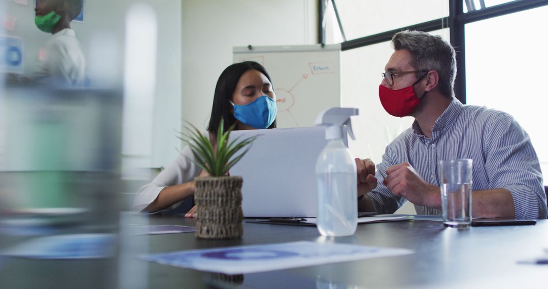 Colleagues in Masks Collaborating in Modern Office with Laptop