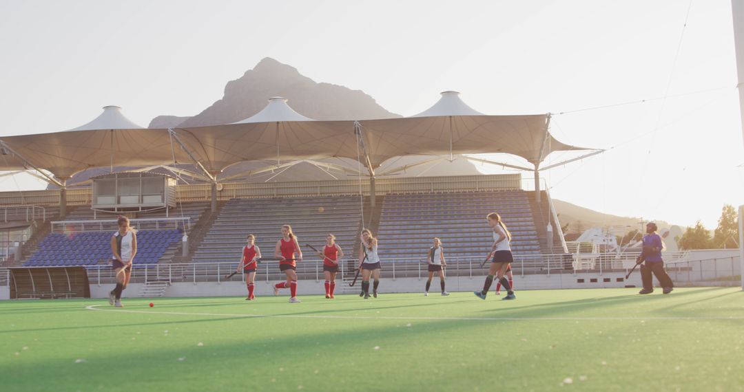 Female Athletes Playing Field Hockey in Stadium at Sunset - Free Images, Stock Photos and Pictures on Pikwizard.com