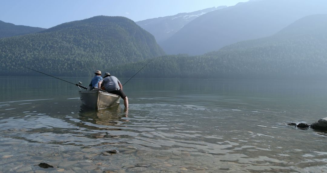 Men fishing in a boat in serene mountain lake - Free Images, Stock Photos and Pictures on Pikwizard.com