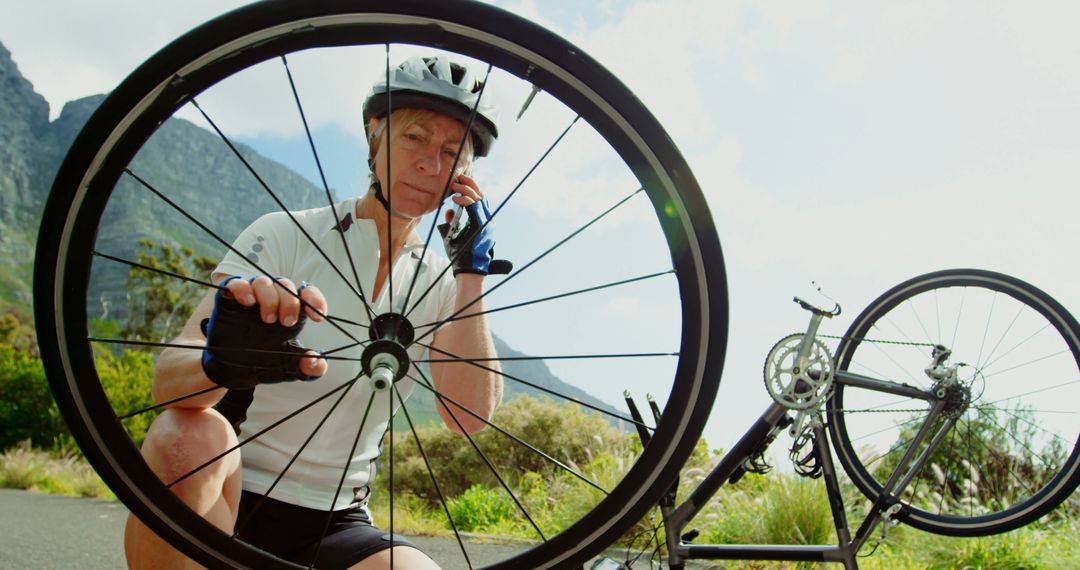 Cyclist Repairing Bicycle Wheel Outdoors on Scenic Route - Free Images, Stock Photos and Pictures on Pikwizard.com