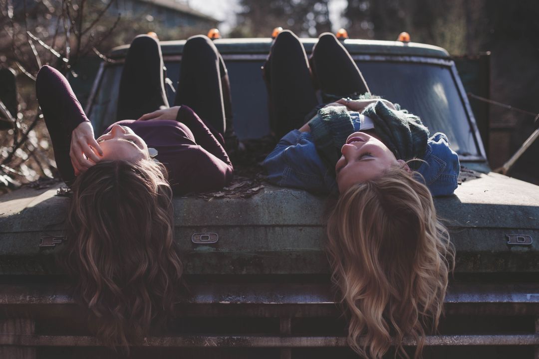 Friends Relaxing on an Old Car Hood Outdoors - Free Images, Stock Photos and Pictures on Pikwizard.com