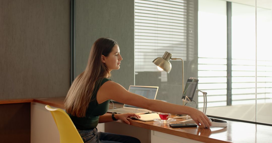 Woman working with laptop and tablet at modern desk