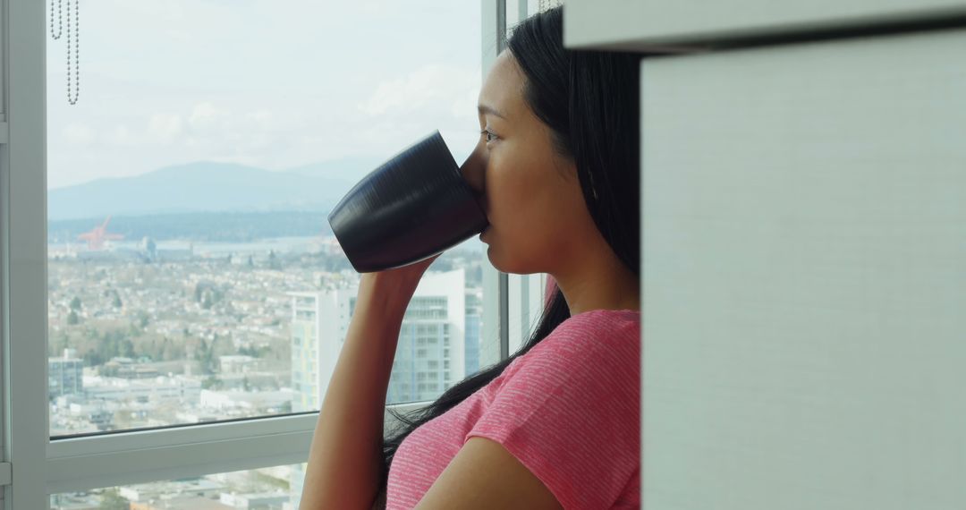 Woman enjoying coffee with city view from modern apartment - Free Images, Stock Photos and Pictures on Pikwizard.com