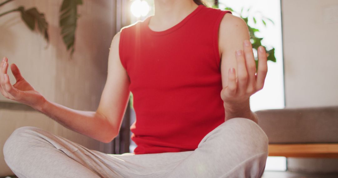 Person in red tank top meditating indoors with sunlight background - Free Images, Stock Photos and Pictures on Pikwizard.com