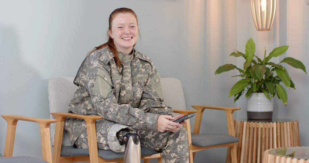 Smiling Female Soldier with Prosthetic Leg Using Smartphone in Relaxed Setting