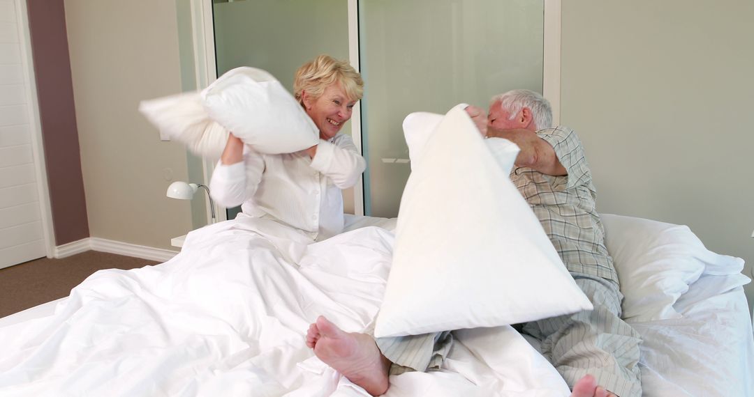 Elderly Couple Pillow Fighting in Bright Bedroom - Free Images, Stock Photos and Pictures on Pikwizard.com