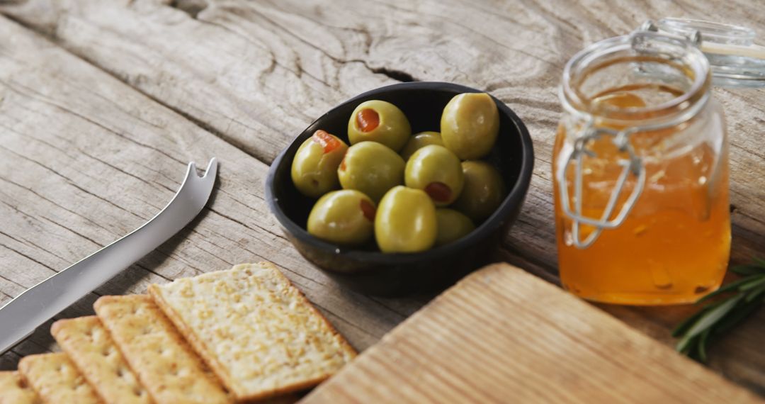 Rustic Snack Setting with Olives, Crackers, and Honey Jar on Wooden Table - Free Images, Stock Photos and Pictures on Pikwizard.com