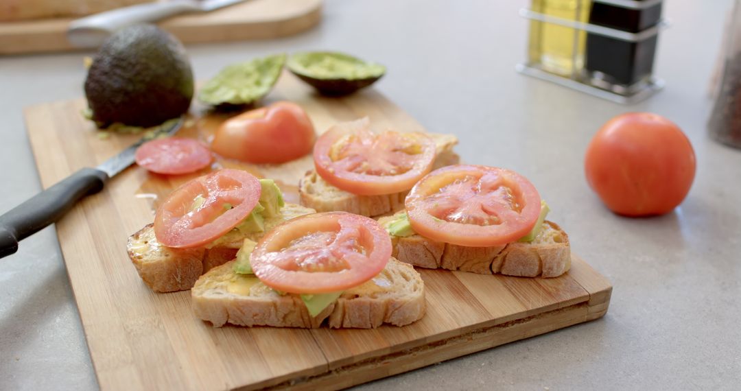 Preparing Avocado Tomato Toasts on Wooden Cutting Board in Kitchen