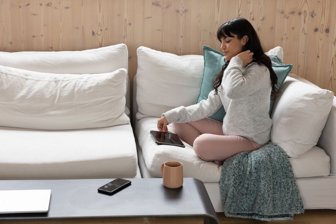 Hispanic Woman on Sofa Relaxed with Tablet and Coffee