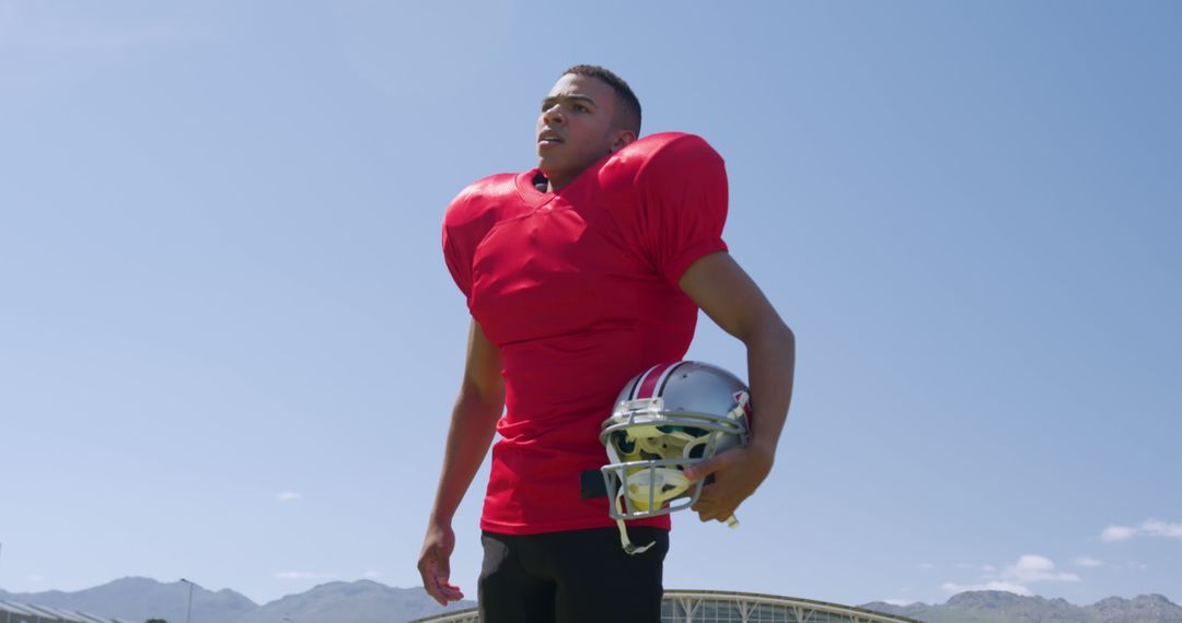 American Football Player Holding Helmet Under Clear Sky - Free Images, Stock Photos and Pictures on Pikwizard.com