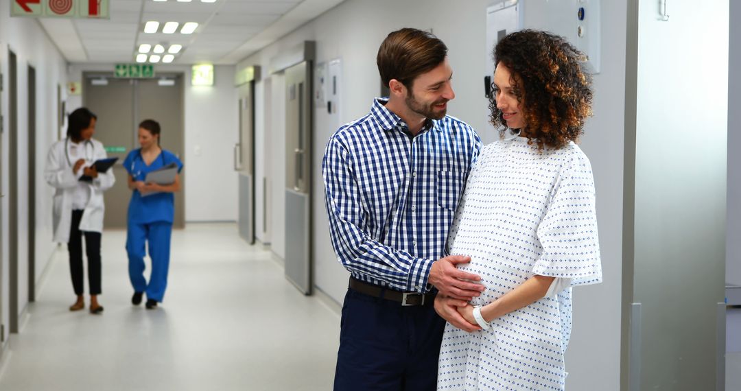 Expectant Couple Smiling in Hospital Hallway - Free Images, Stock Photos and Pictures on Pikwizard.com