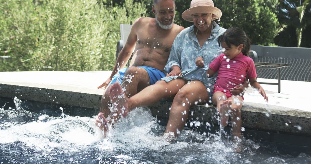 Grandparents and Granddaughter Enjoy Splashing Poolside Fun