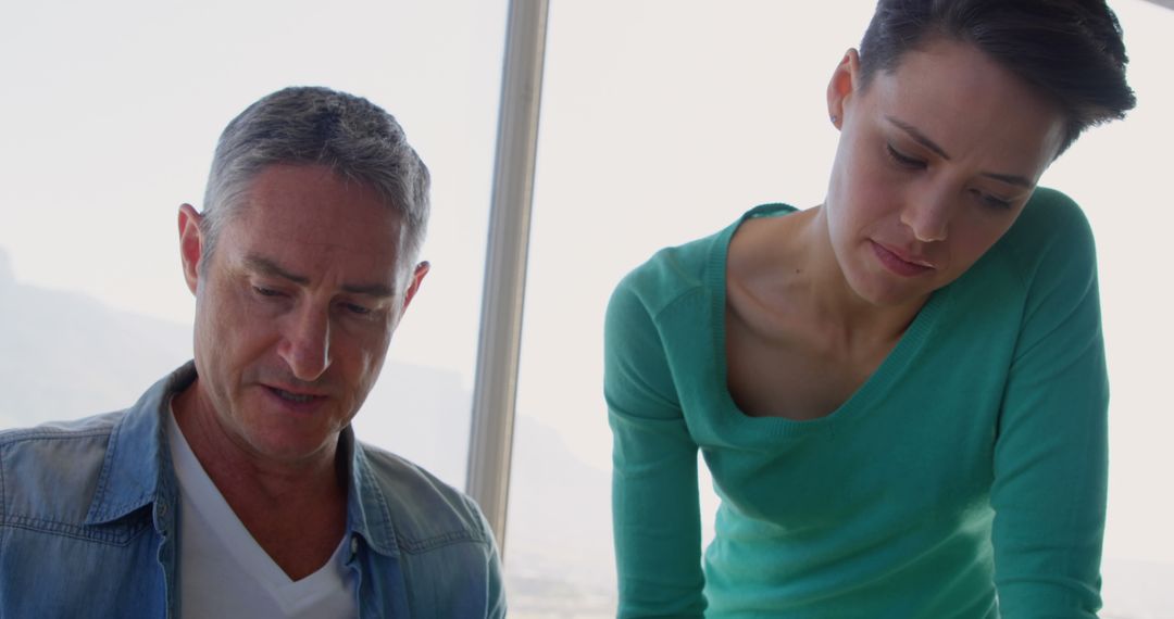 Colleagues Reviewing Blueprint in Bright Office Workspace