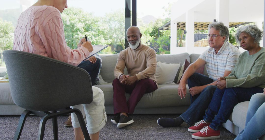 Clinician Taking Notes During Diverse Group Therapy Session in Sunlit Living Room