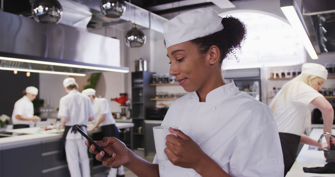 Young Chef Checking Phone in Commercial Kitchen While Drinking Coffee - Free Images, Stock Photos and Pictures on Pikwizard.com