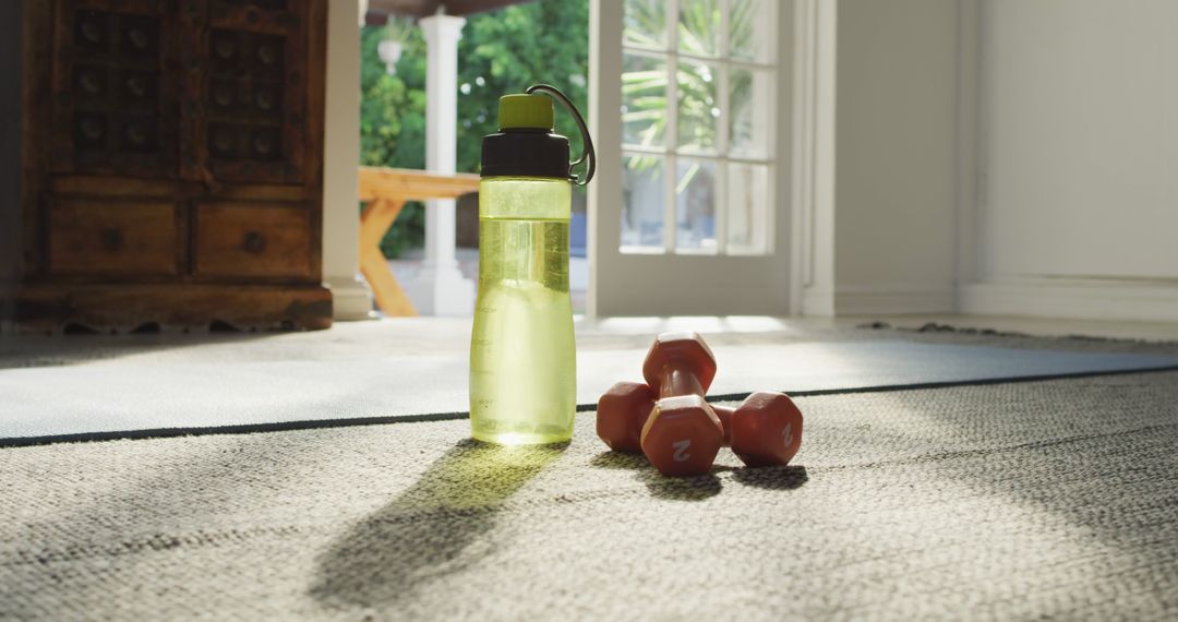 Image of bottle of water, weights and yoga mat prepared for exercising at home - Free Images, Stock Photos and Pictures on Pikwizard.com