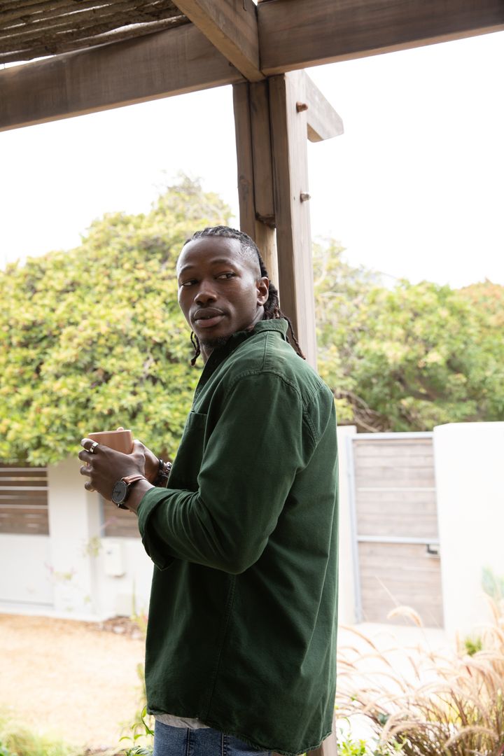 Man Enjoying Coffee on Cozy Patio Surrounded by Greenery