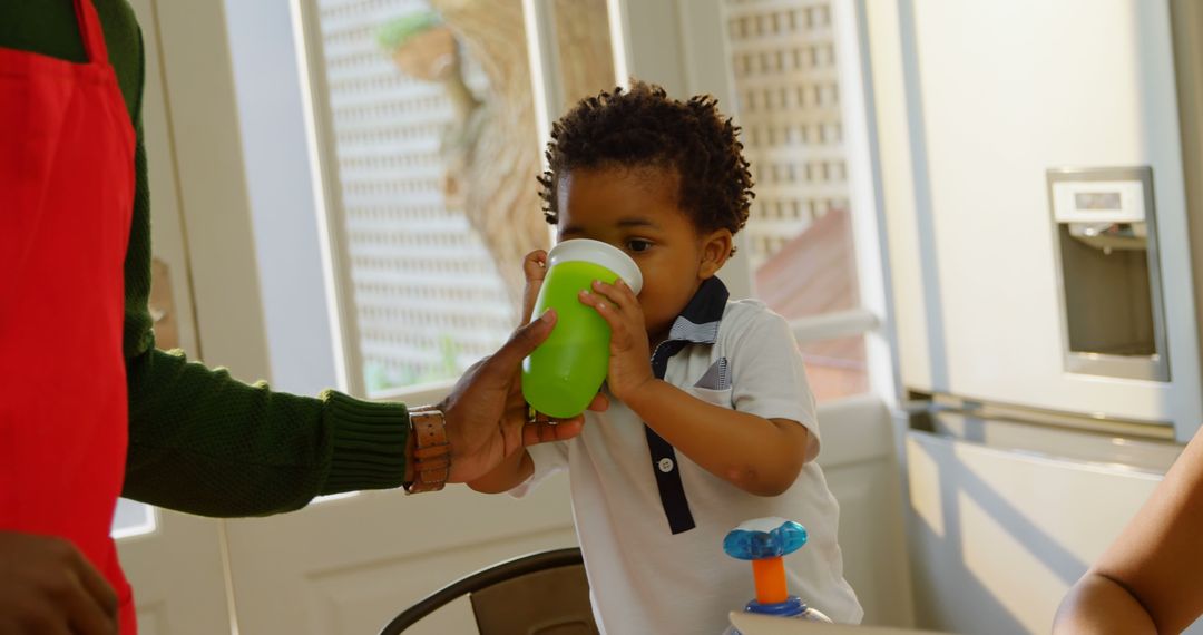 Curious Toddler Drinking from Sippy Cup in Cozy Kitchen - Free Images, Stock Photos and Pictures on Pikwizard.com