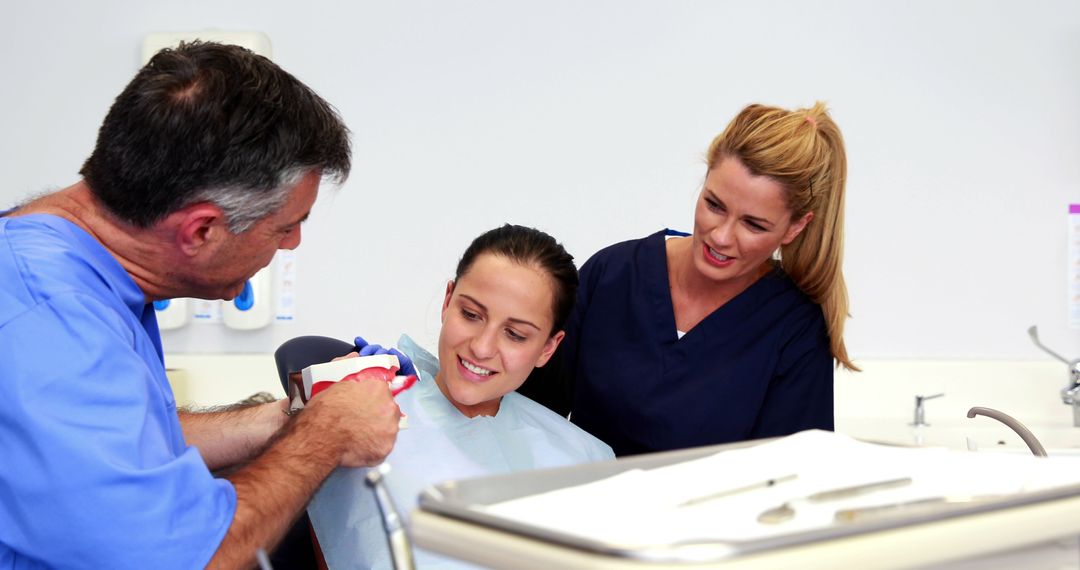 Dentist Explaining Dental Procedure with Model to Young Patient - Free Images, Stock Photos and Pictures on Pikwizard.com