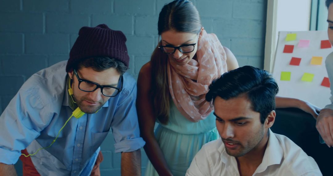 Asian man typing while team collaborating and brainstorming at creative coworking space