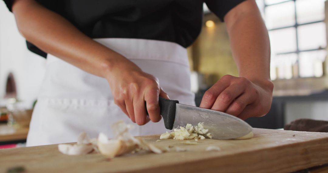 Chef slicing garlic on wooden board in modern kitchen - Free Images, Stock Photos and Pictures on Pikwizard.com