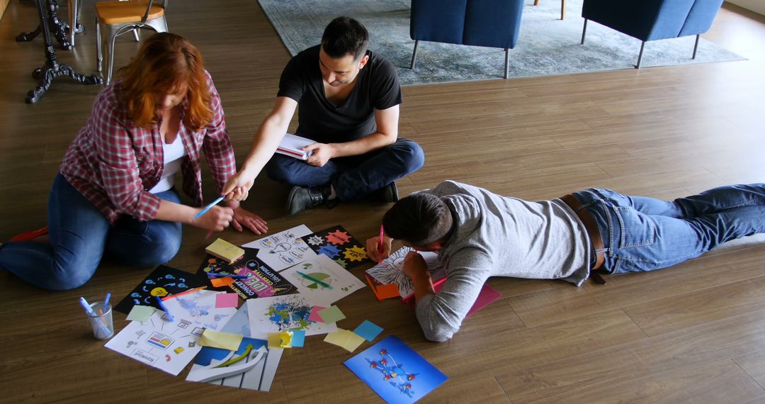 Creative Team Brainstorming Ideas with Coloring Sheets on Floor - Free Images, Stock Photos and Pictures on Pikwizard.com