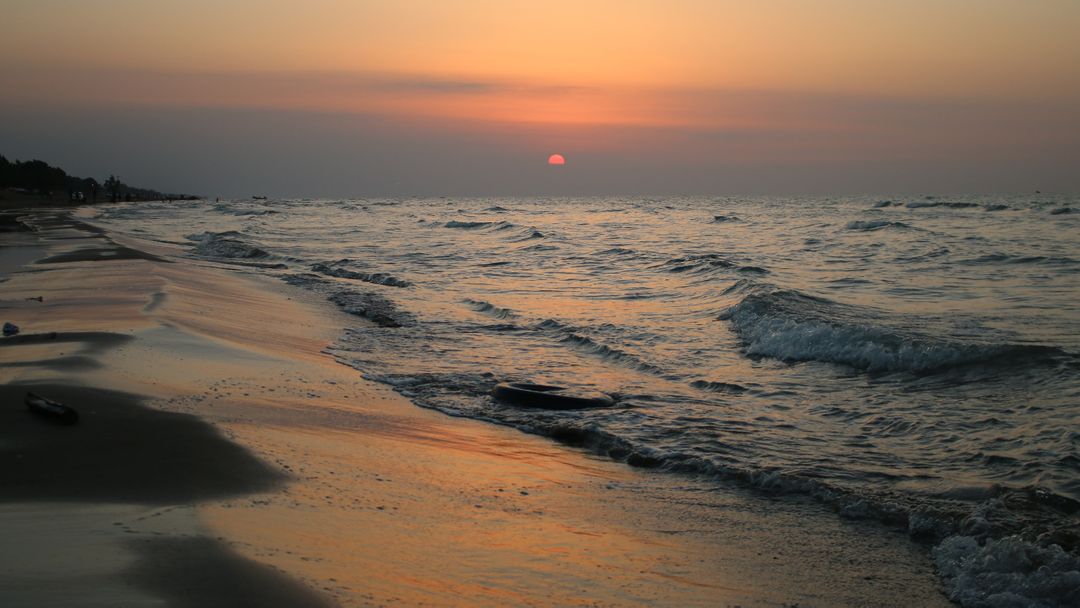 Serene Beach at Sunset with Gentle Waves and Orange Sky - Free Images, Stock Photos and Pictures on Pikwizard.com