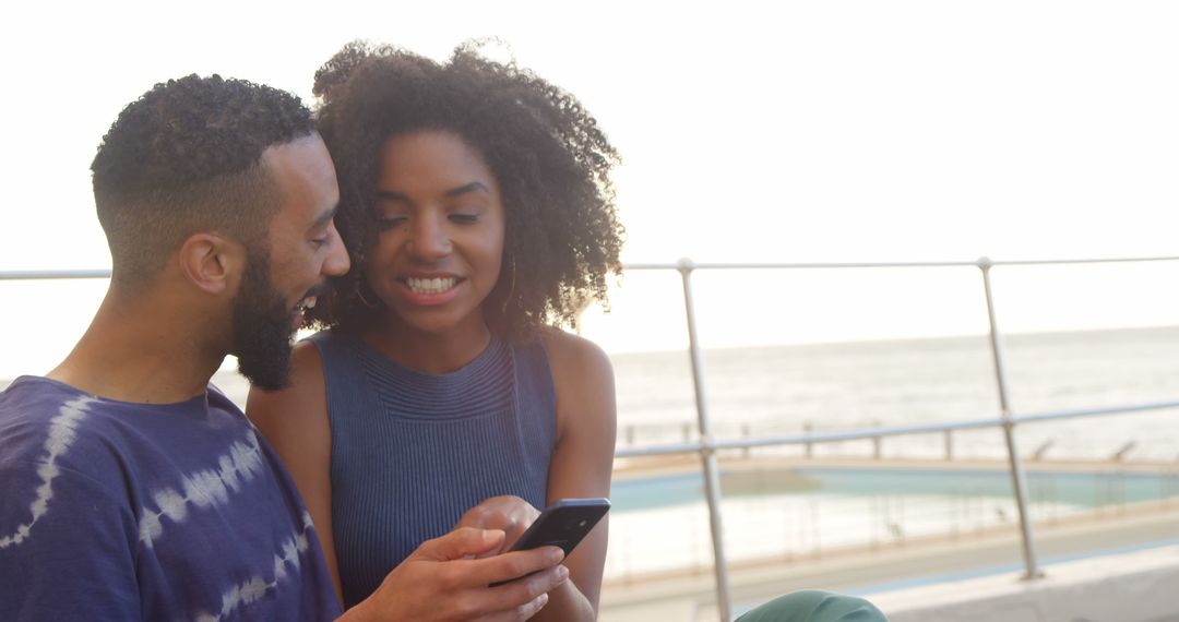 Romantic Couple Enjoying Smartphone Interaction at Beachfront