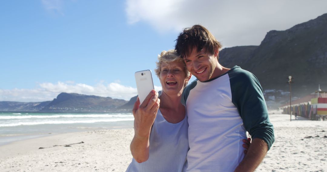 Mother and Son Taking Selfie on Beach with Mountain View - Free Images, Stock Photos and Pictures on Pikwizard.com